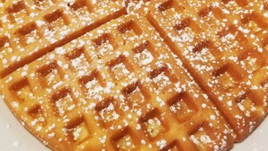 Une assiette avec une gaufre, des fraises et de la crème fouettée.