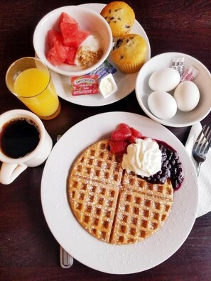 A breakfast plate with waffles, strawberries, whipped cream, and blueberries. - Kings Port Inn (Kennebunk)