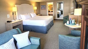 Une chambre d’hôtel comprenant un lit, deux tables de chevet, un bureau avec une chaise, un canapé et un miroir.