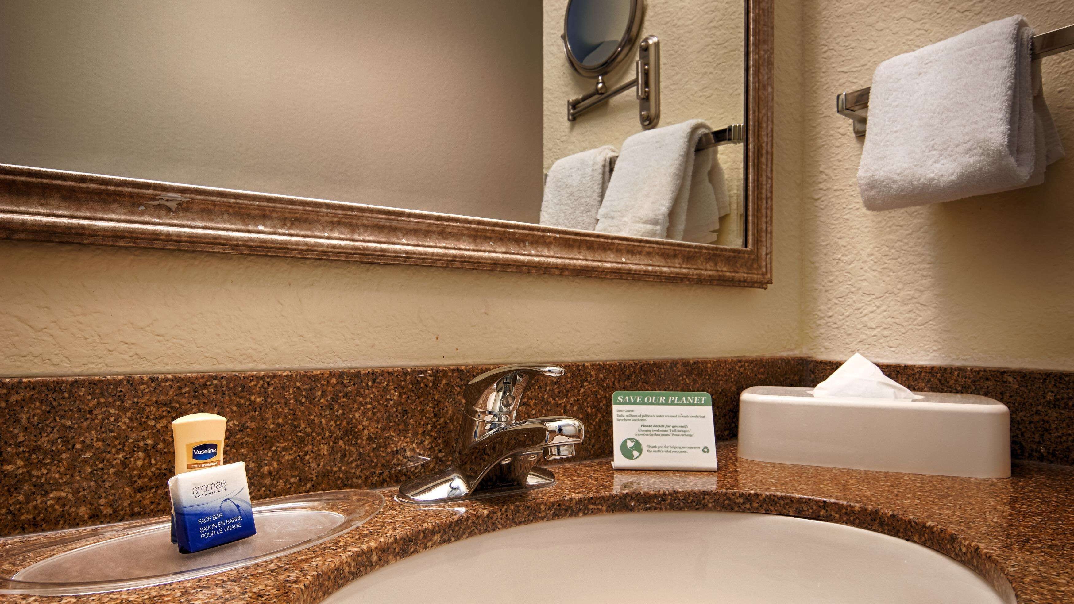 A bathroom sink with a mirror, a towel rack, and a tissue box.