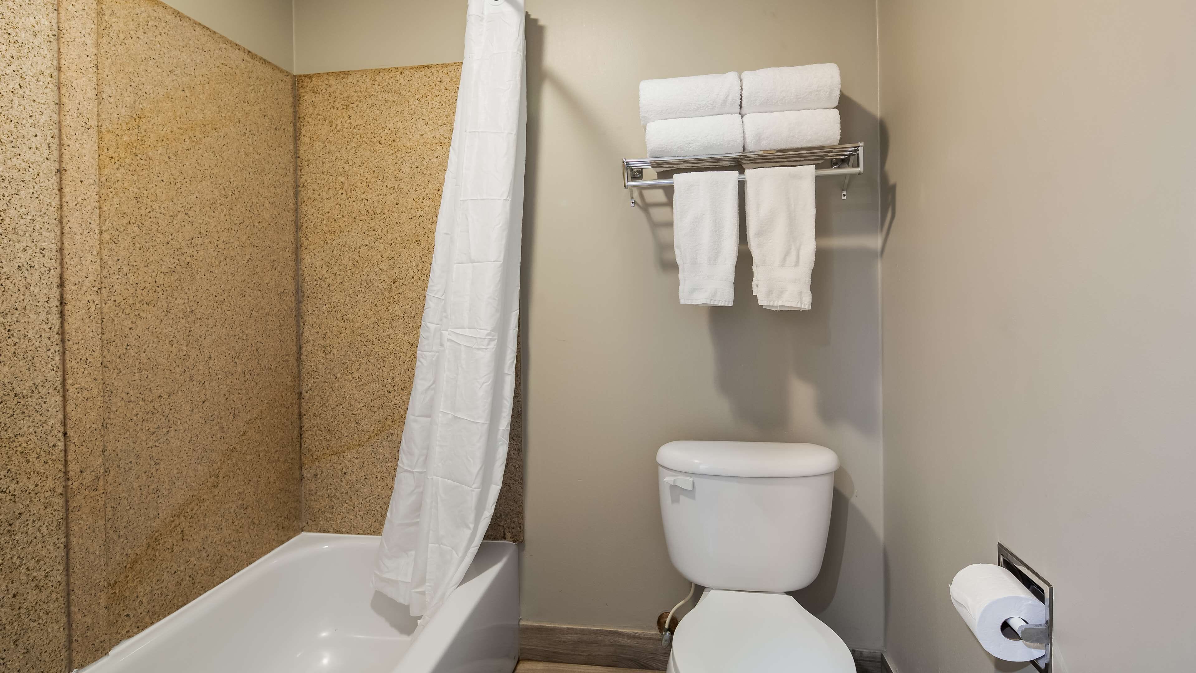 A bathroom with a bathtub, toilet, and towel rack.