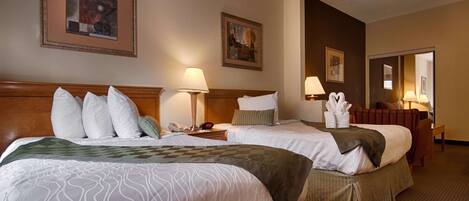 A hotel room with two beds, a nightstand with a lamp, a phone, and a wall clock. There are framed pictures on the wall and a chair in the corner.
