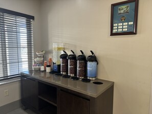 A beverage station with dispensers for coffee, tea, and water, and a framed award on the wall. - Comfort Inn & Suites St. Paul Northeast (White Bear Lake)