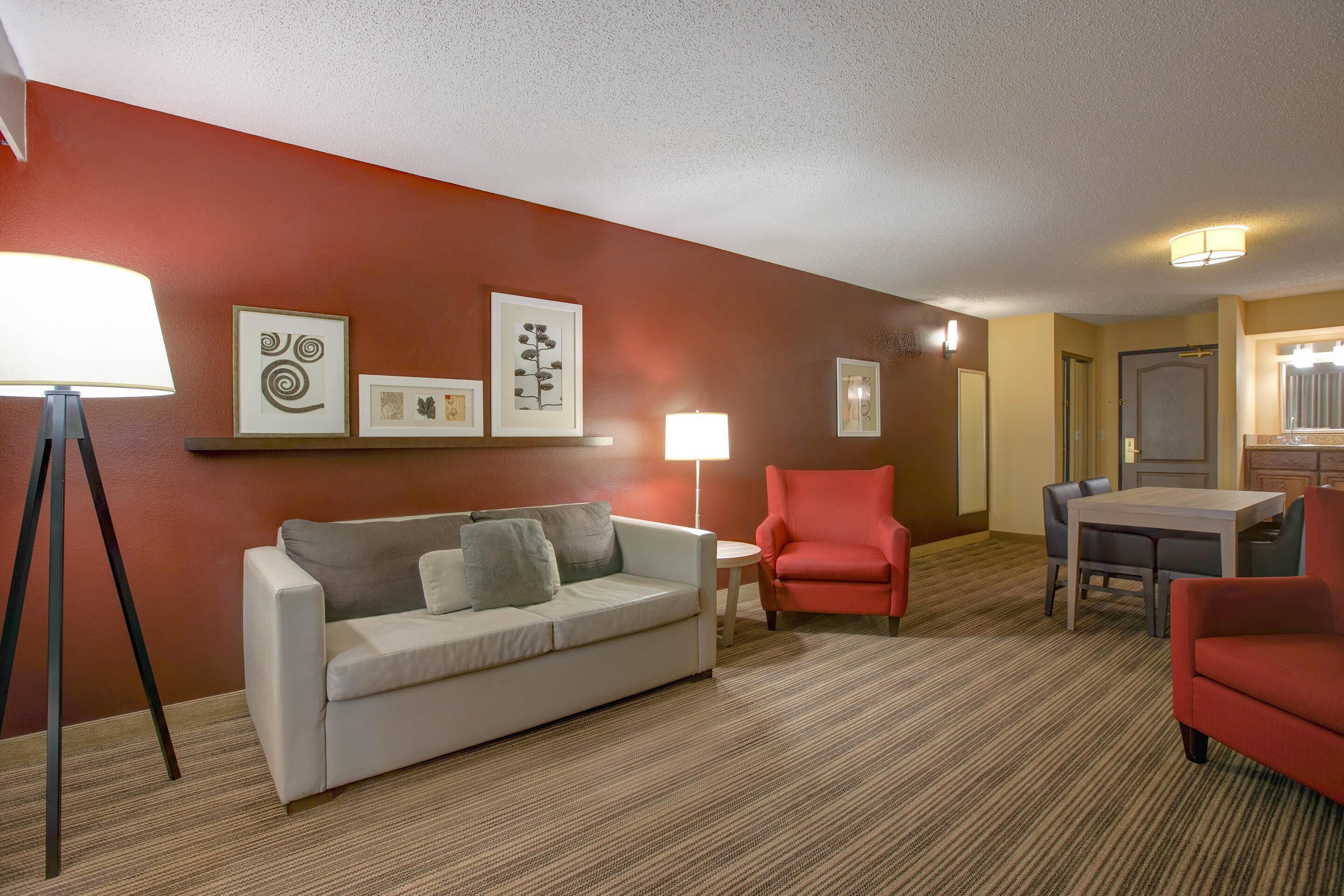 Habitación de hotel con sofá, sillones, una mesa de comedor y una lámpara.