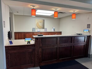 A reception area with a wooden counter, a digital screen, and three pendant lights. - Comfort Inn & Suites St. Paul Northeast (White Bear Lake)