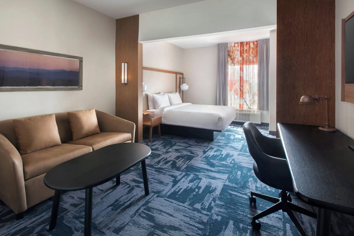 A hotel room with a bed, a sofa, a desk, and a chair.