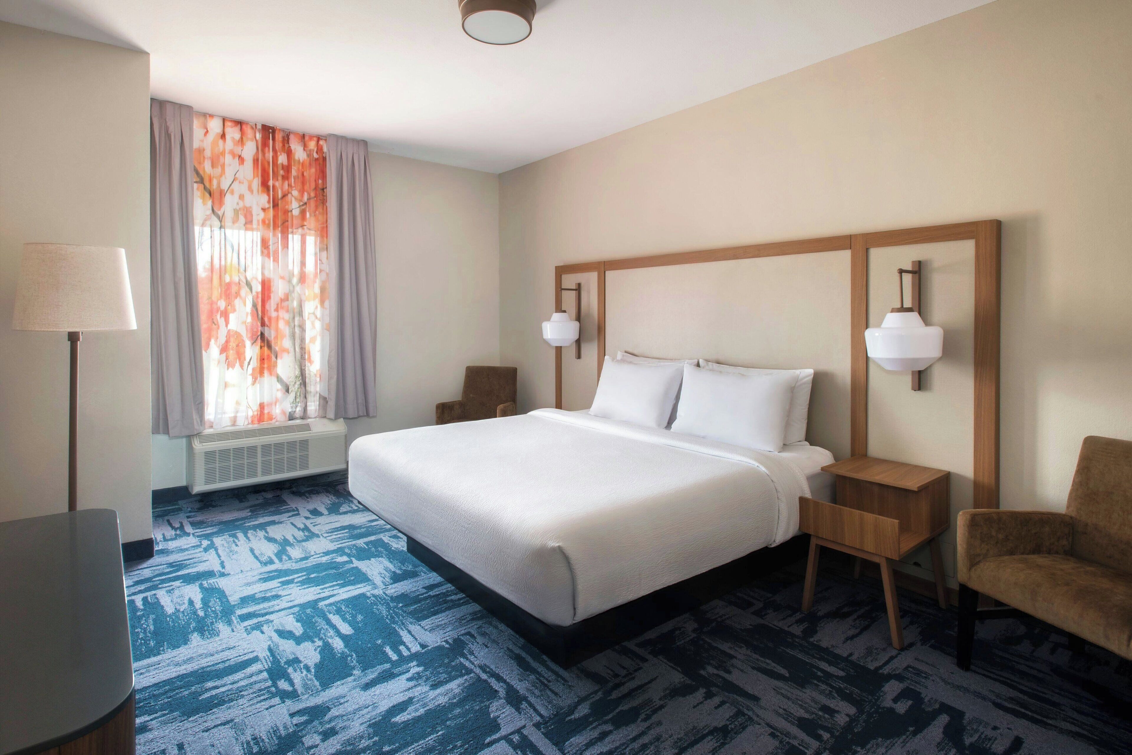 A hotel room with a large bed, two bedside tables, a desk, and a chair.