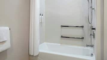 Ein modernes Badezimmer mit einer Wand aus weißen Fischgrätplatten, einer weißen Badewanne und einer Dusche mit Duschbrause.