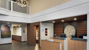 A hotel reception area with a wooden reception desk, a minibar, and a view of a balcony. - Fairfield Inn & Suites by Marriott Somerset (Somerset)