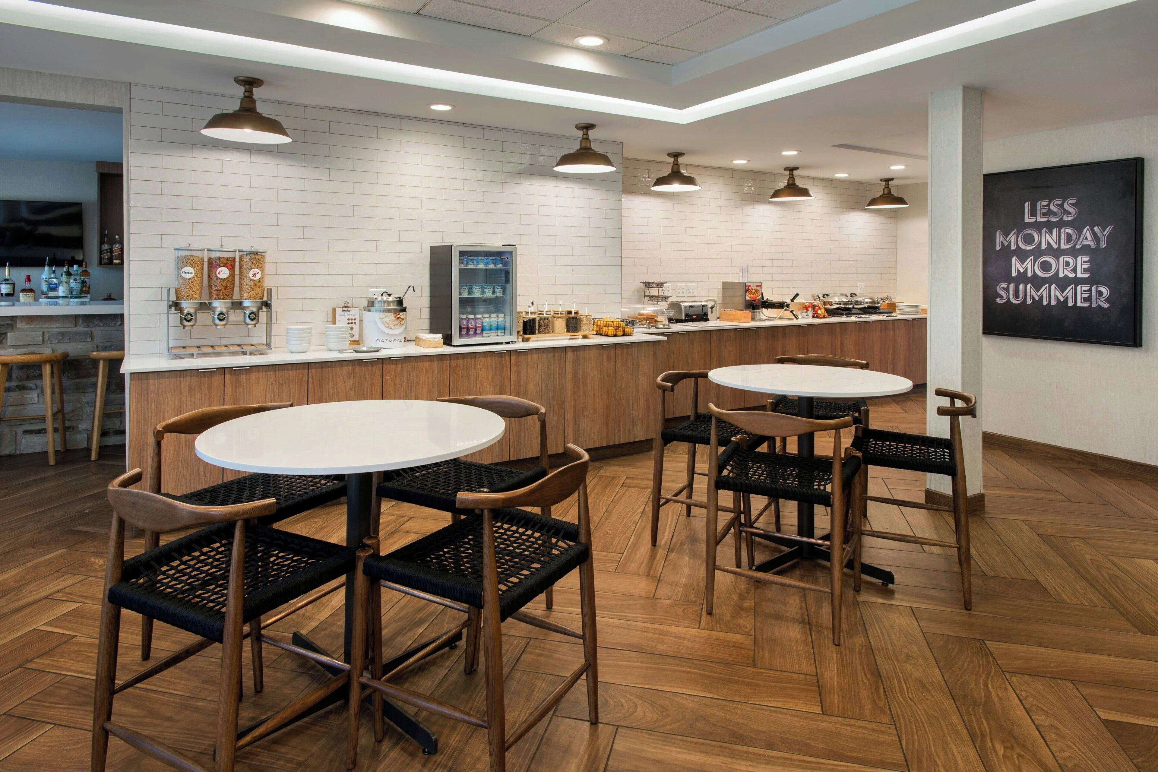 Un cafè modern amb taules i cadires rodones, una màquina de cafè i un dispensador de menús.