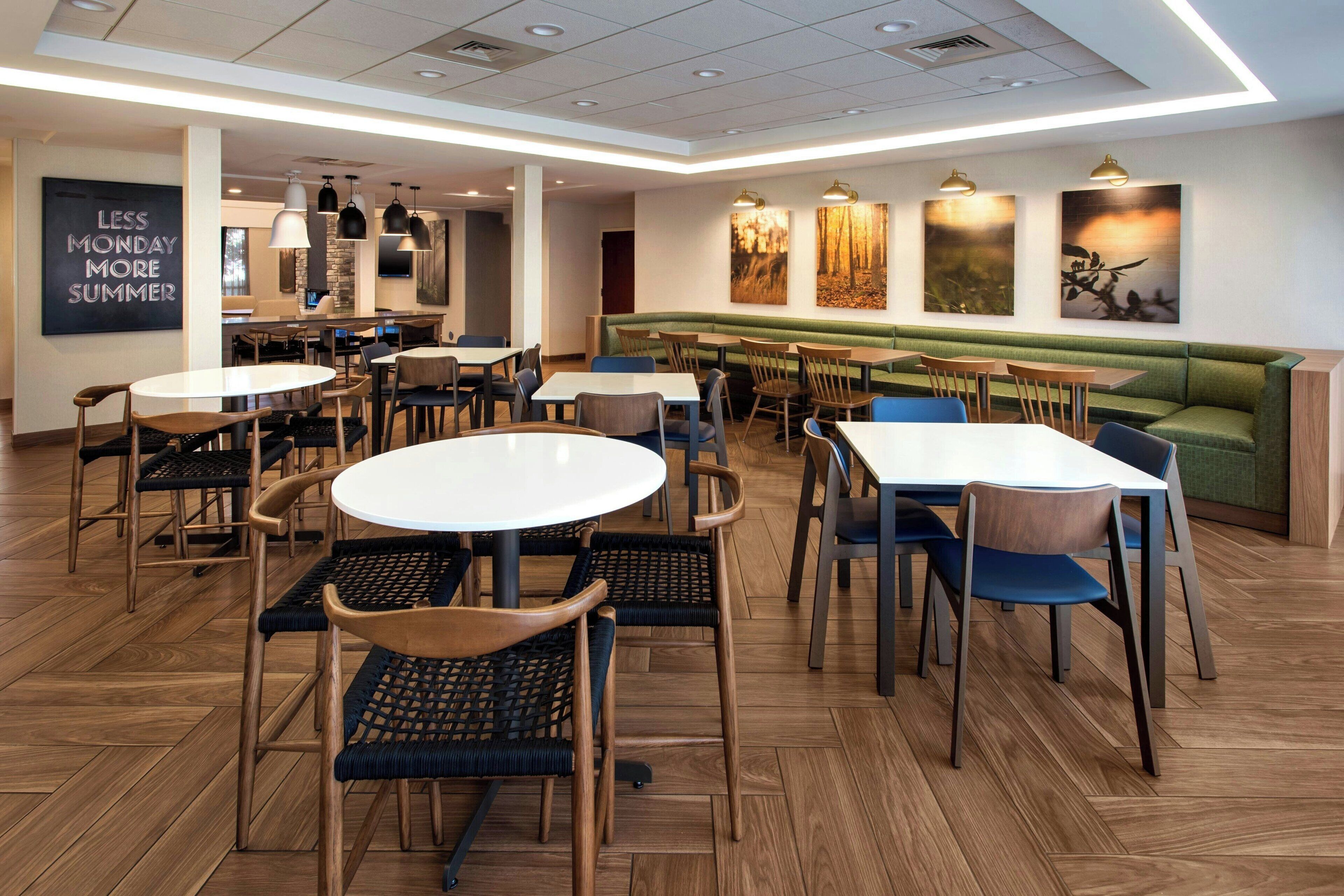 A modern dining area with round tables, chairs, and a green booth.