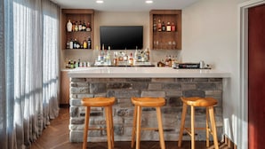 A bar area with a stone countertop, wooden stools, and shelves of liquor bottles. - Fairfield Inn & Suites by Marriott Somerset (Somerset)