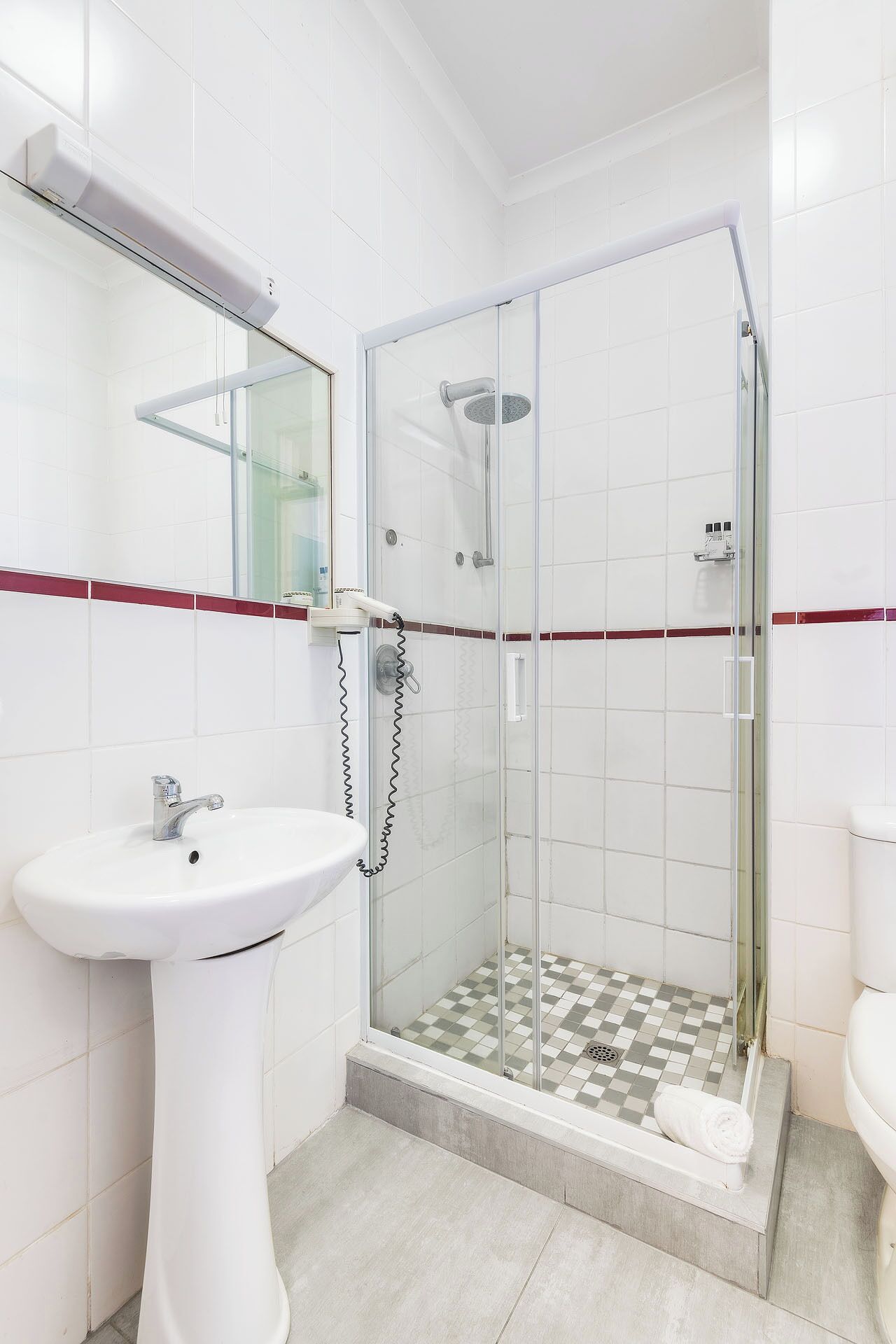 A bathroom with a glass-enclosed shower, a white sink, and a toilet.