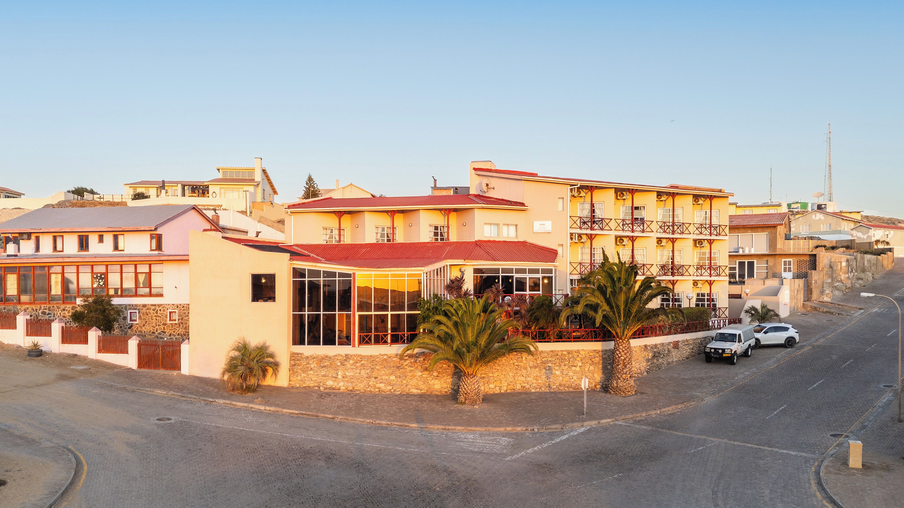 A multi-story hotel with a red roof, large windows, and a stone facade.