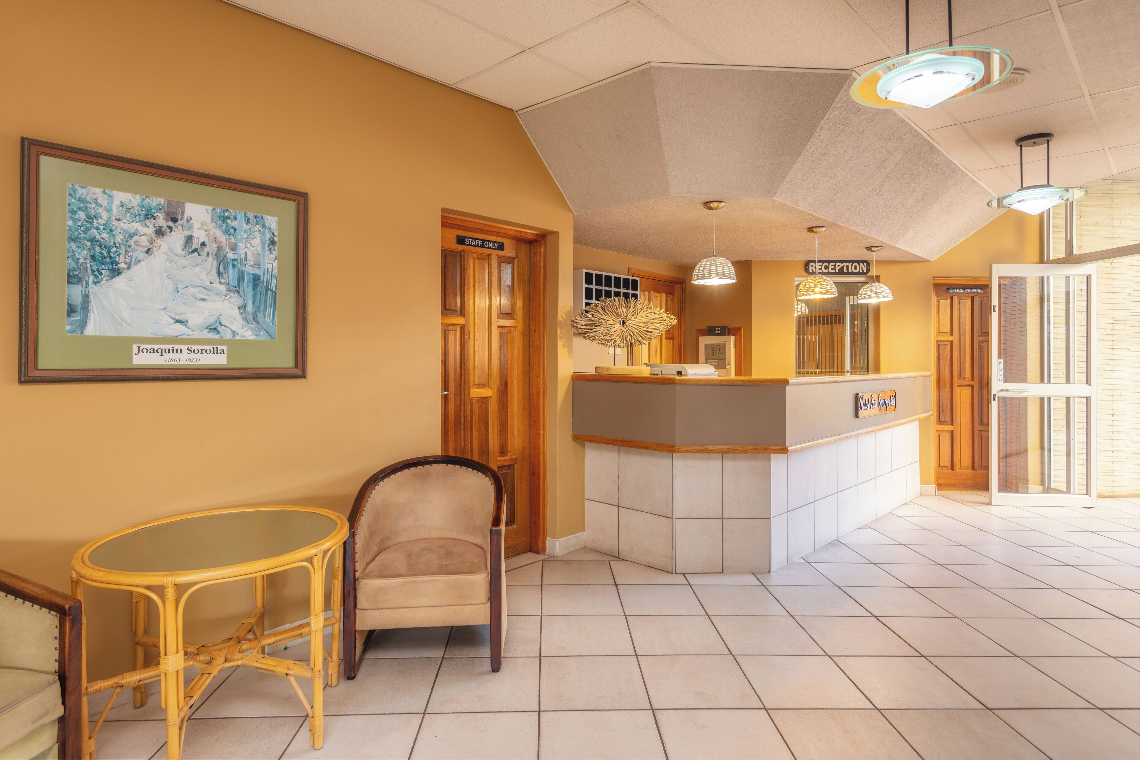 A reception area with a reception desk, a chair, a framed picture on the wall, and a sign that reads 'STAFF ONLY.'