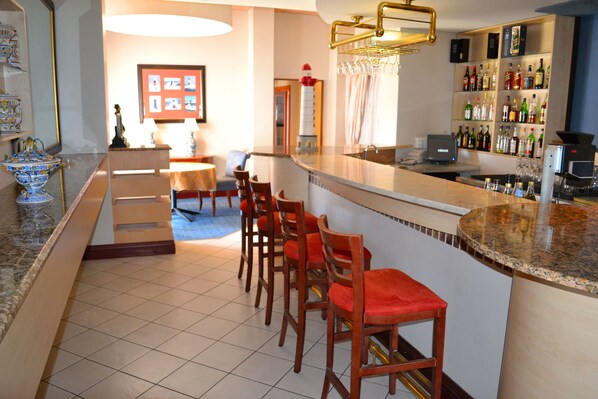 A bar area with a counter, bar stools, and a shelf with bottles. - Protea Hotel by Marriott Walvis Bay Pelican Bay (Walvis Bay)