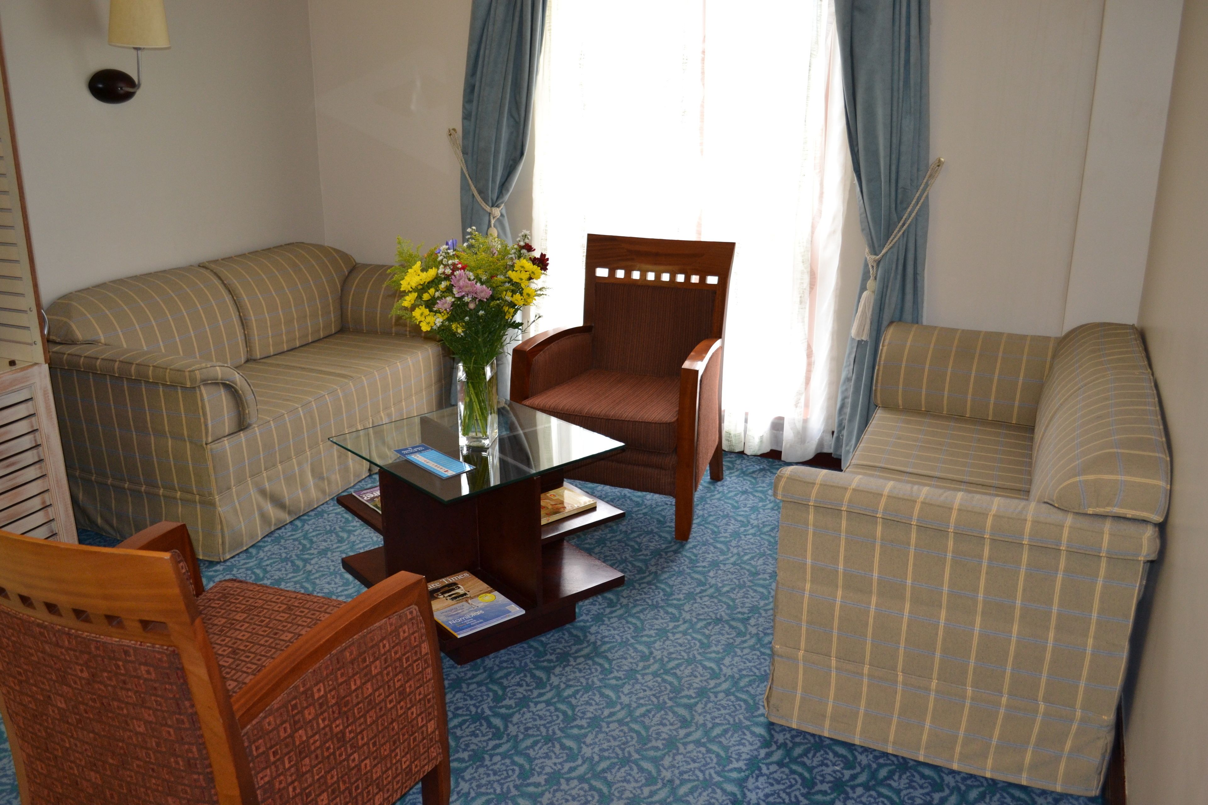 A living room with a sofa, armchairs, a coffee table, and a vase of flowers.