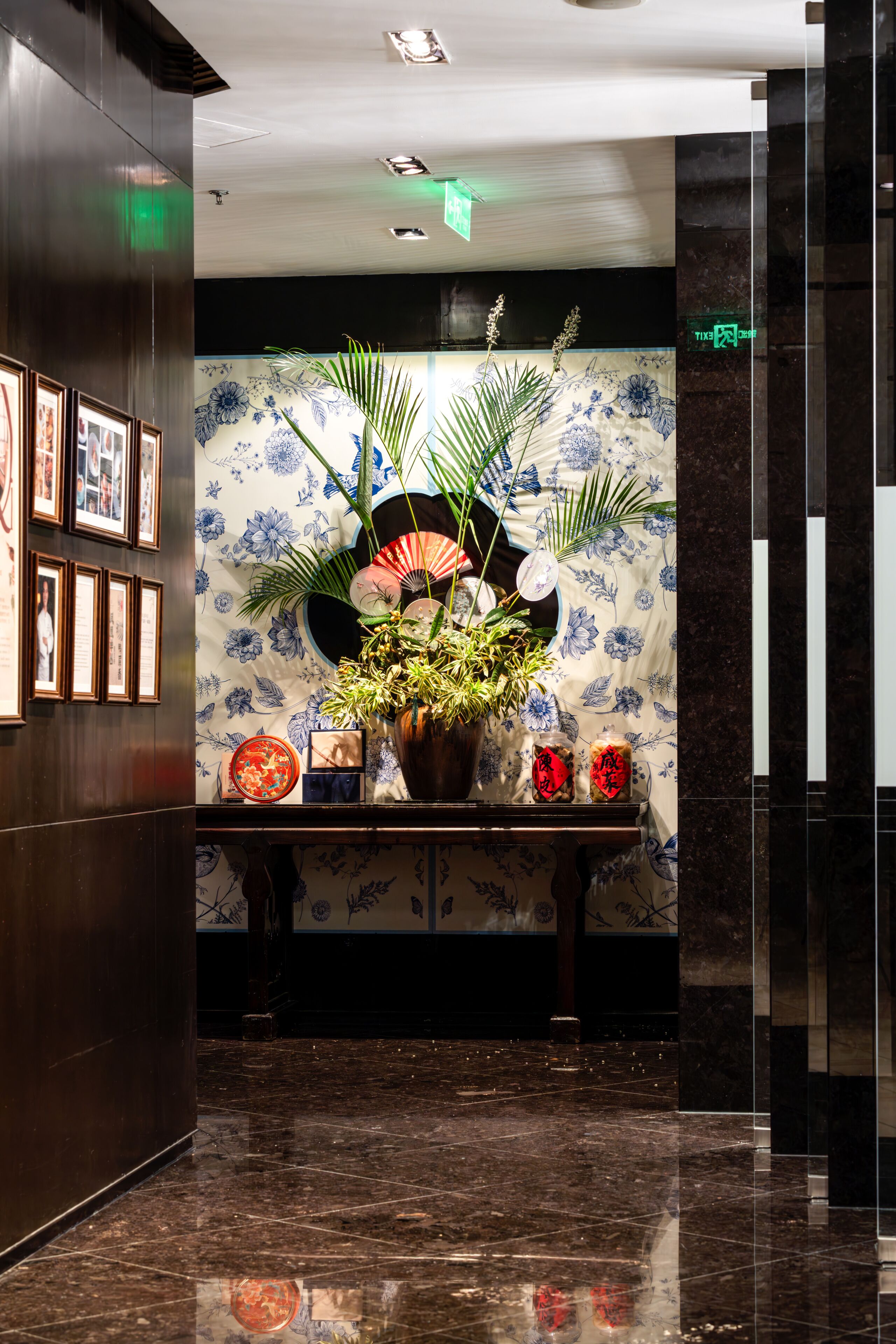 Un hall d’entrée avec un comptoir de réception, des tableaux encadrés, un mur végétal et une plante en pot.