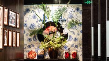 Un hall d’entrée avec un comptoir de réception, des tableaux encadrés, un mur végétal et une plante en pot.