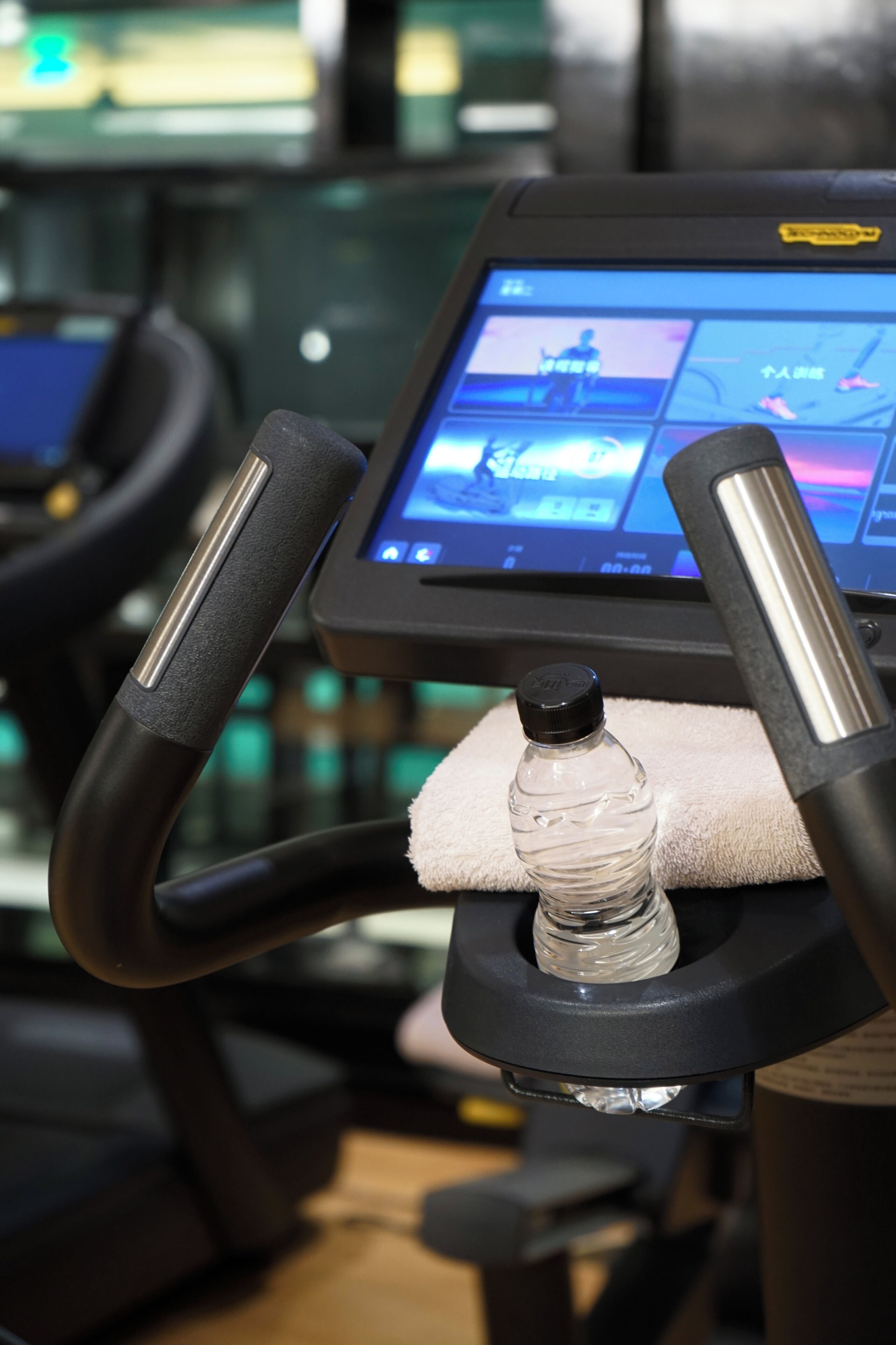 Una cinta de correr con pantalla digital, portavasos para botellas de agua y una toalla.