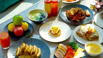 Una mesa con diversos platos, entre ellos frutas, verduras y un vaso de jugo de naranja.