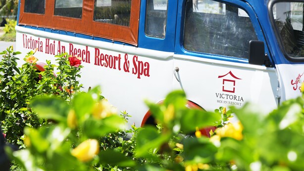 A blue and white bus with "Victoria Hoi An Beach Resort & Spa" written on the side.