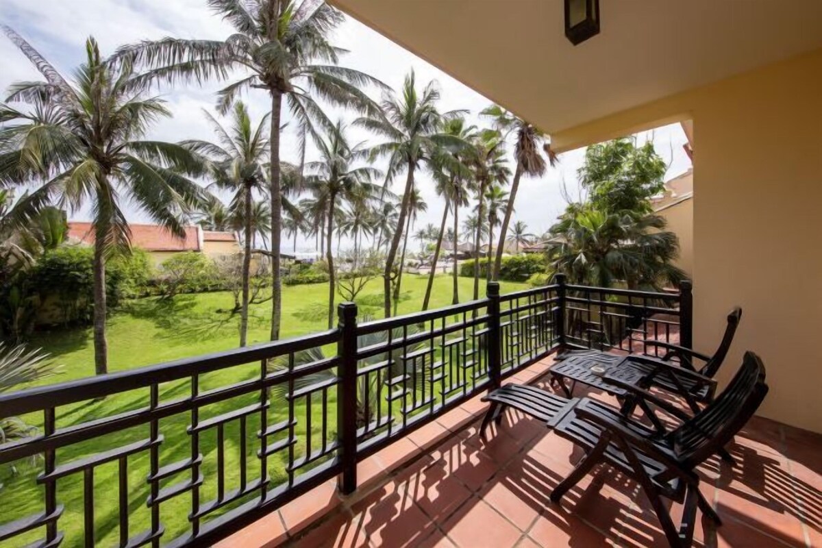 A balcony with a view of palm trees and a green lawn.