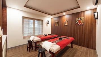 Relax in a serene space with two massage tables, a wooden floor, and framed artwork adorning the walls.