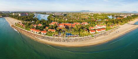 An aerial view of a resort with multiple buildings, a beach, and a water body.