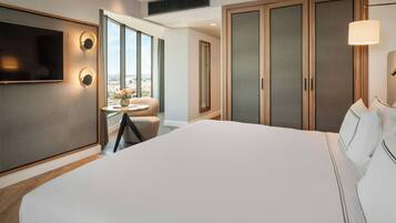 Een hotelkamer met een groot bed, een aan de muur bevestigde televisie, uitzicht op de stad door het raam en een inloopkast.