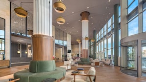 A spacious lobby with high ceilings, large windows, and modern furniture. - Melia Valencia (Valencia)