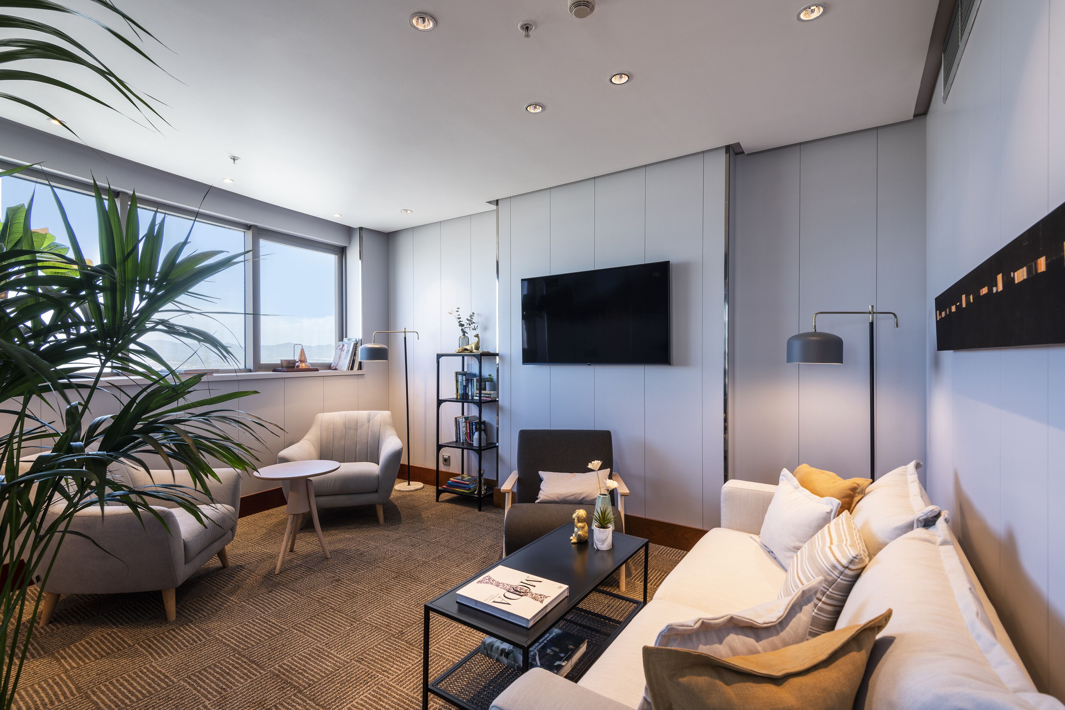 Een moderne woonkamer met een bank, fauteuil, salontafel en een boekenkast.