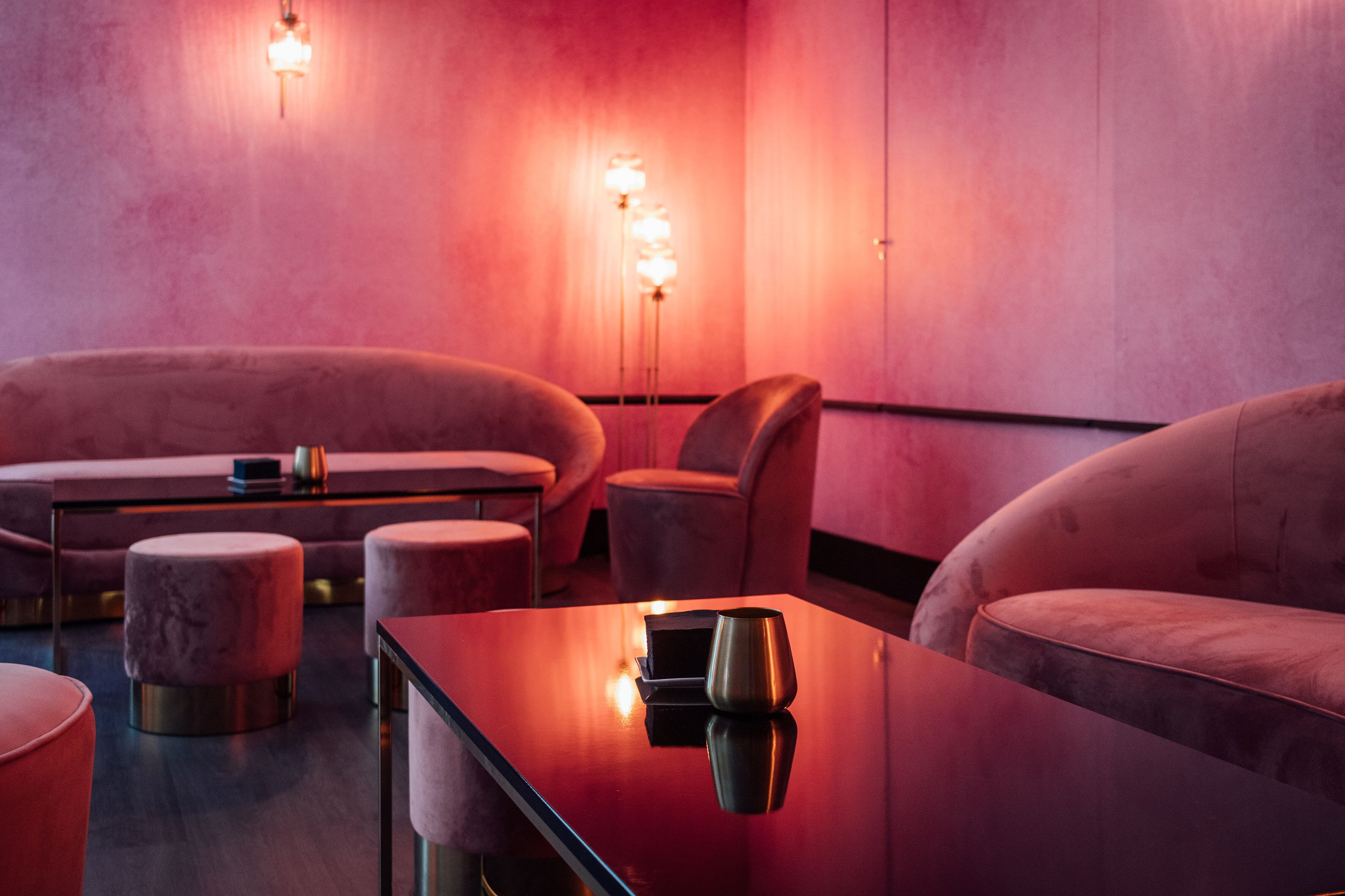 Un área de lounge moderna con asientos cómodos, una mesa reflectante e iluminación ambiental.