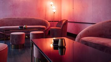 Un área de lounge moderna con asientos cómodos, una mesa reflectante e iluminación ambiental.