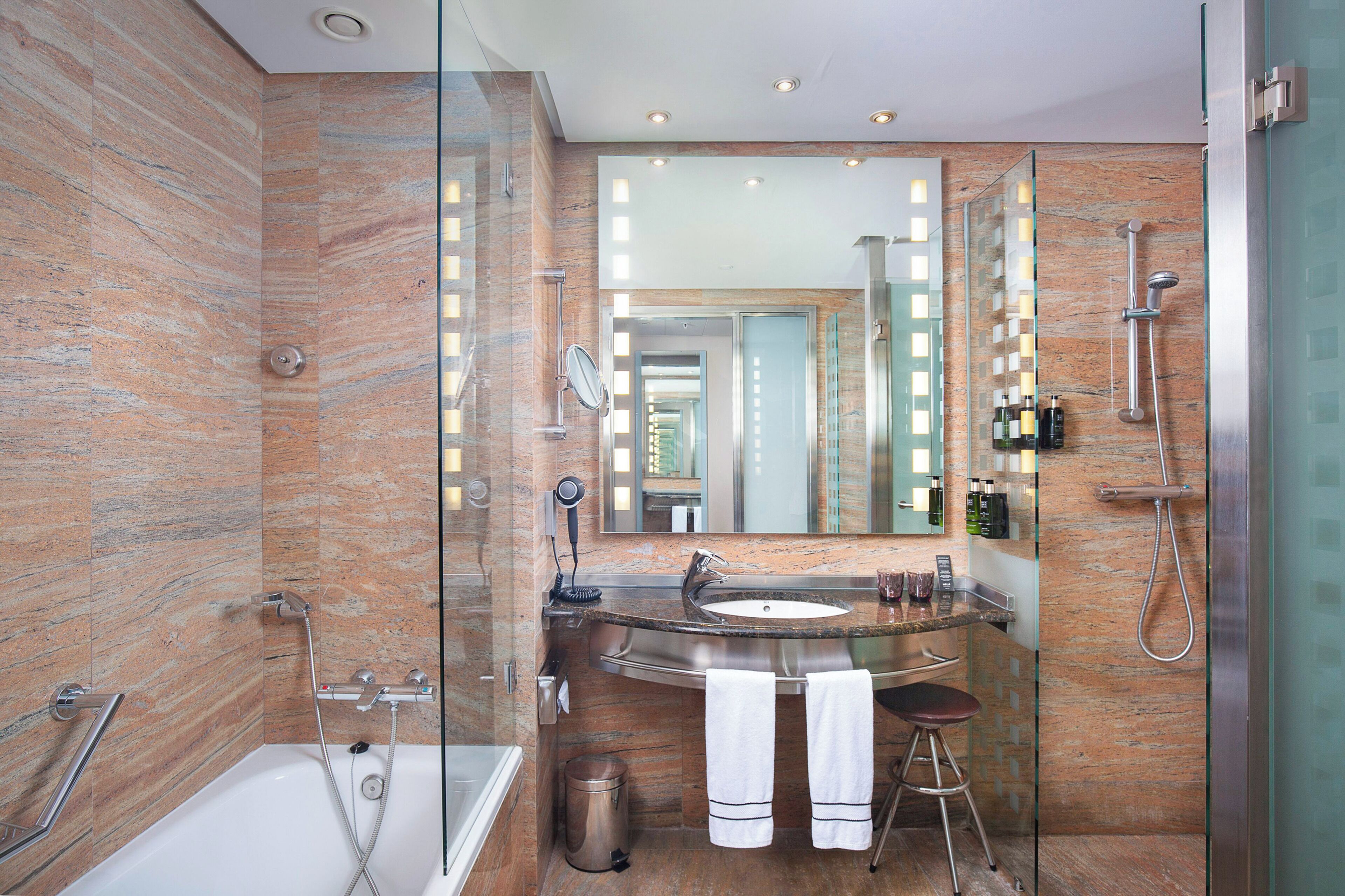 Un baño moderno con ducha de vidrio, lavamanos curvo y un espejo grande.