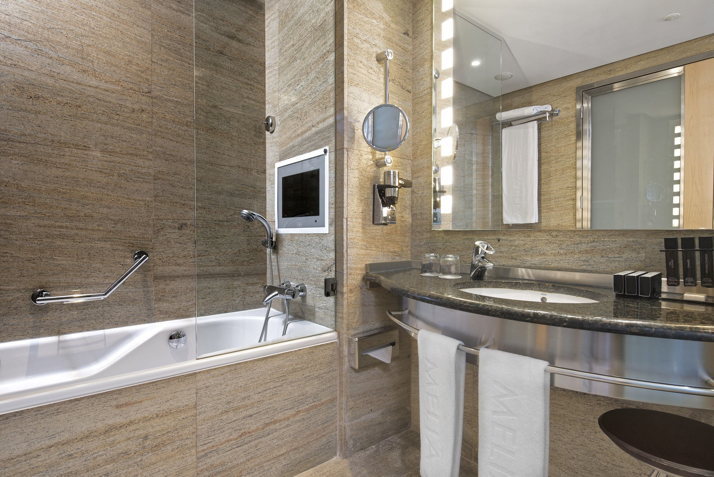 Un baño moderno con bañera, lavamanos y un espejo grande.