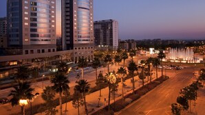 A modern hotel with a prominent tower, multiple floors, and a well-lit facade. - Melia Valencia (Valencia)