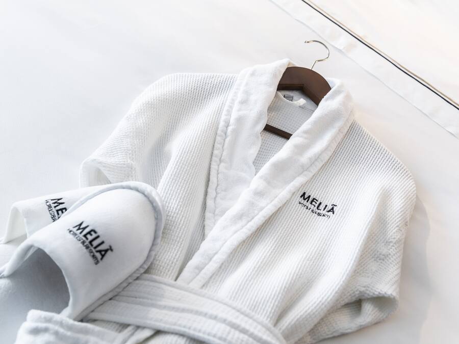 A white bathrobe with "MELIA" branding on a hanger.