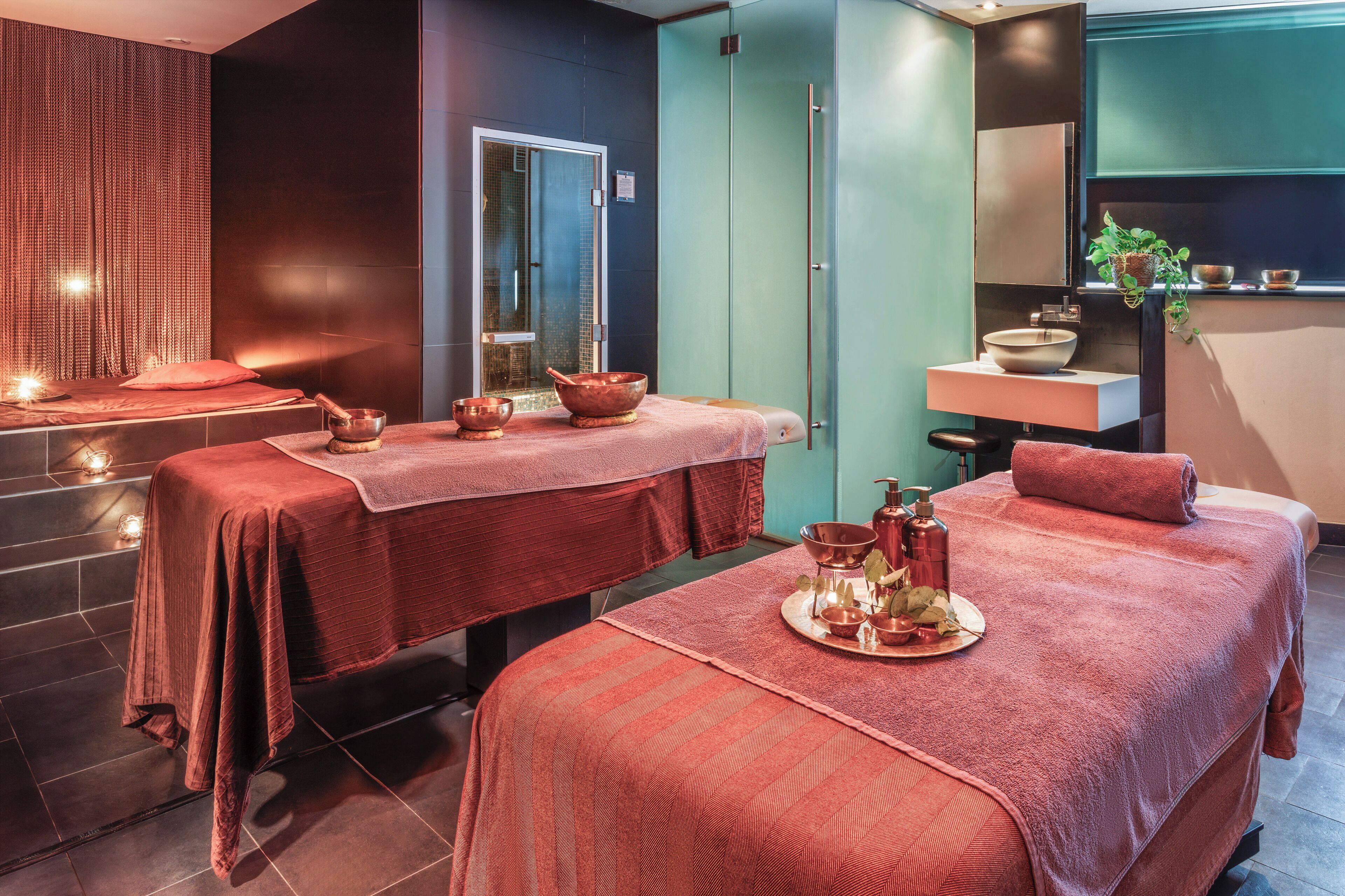 Un cuarto de spa con dos camillas de masaje, un lavamanos y un espejo.