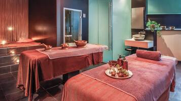 Un cuarto de spa con dos camillas de masaje, un lavamanos y un espejo.
