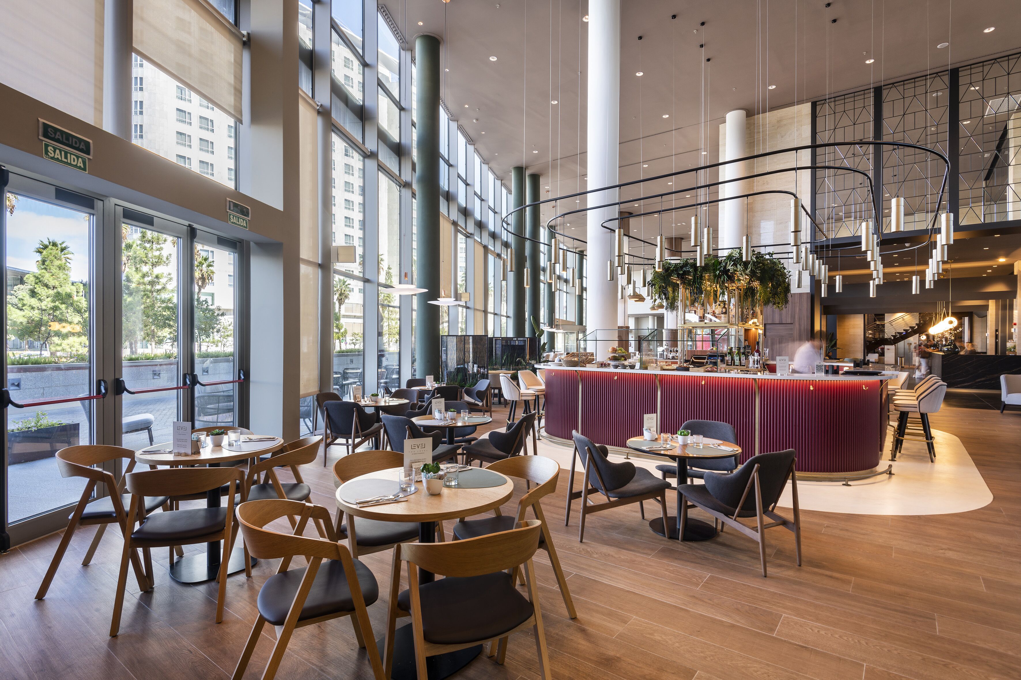 A spacious indoor area with multiple seating arrangements, a central bar area, and large windows providing natural light.