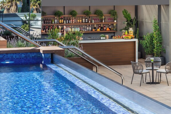 A pool area with a bar, seating, and a staircase leading to an upper level. - Melia Valencia (Valencia)