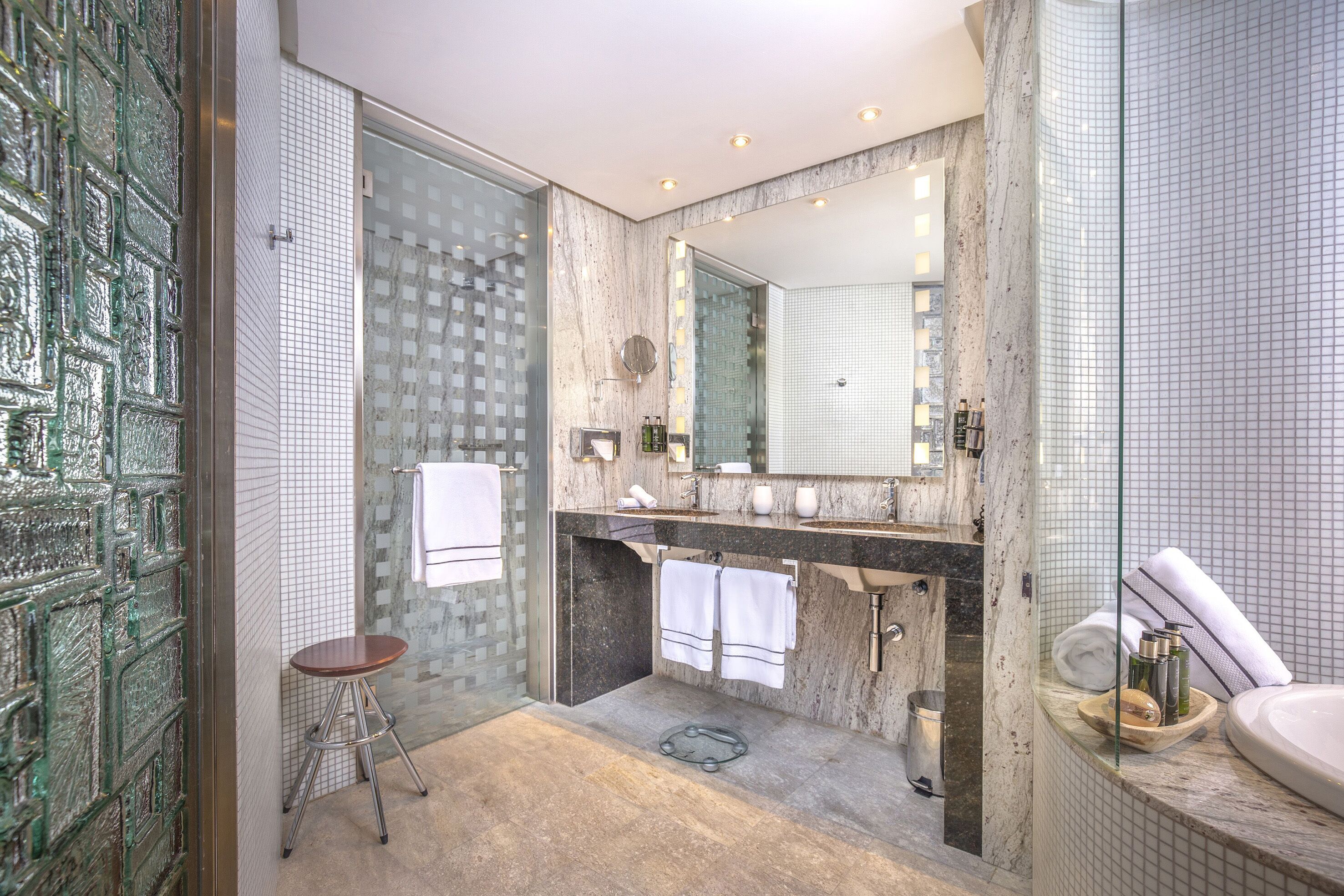 A modern bathroom with a glass shower enclosure, a marble vanity, and a large mirror.