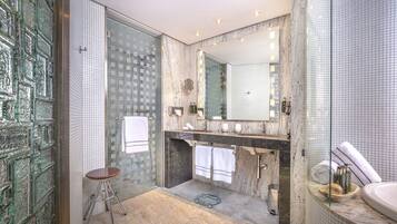 A modern bathroom with a glass shower enclosure, a marble vanity, and a large mirror.