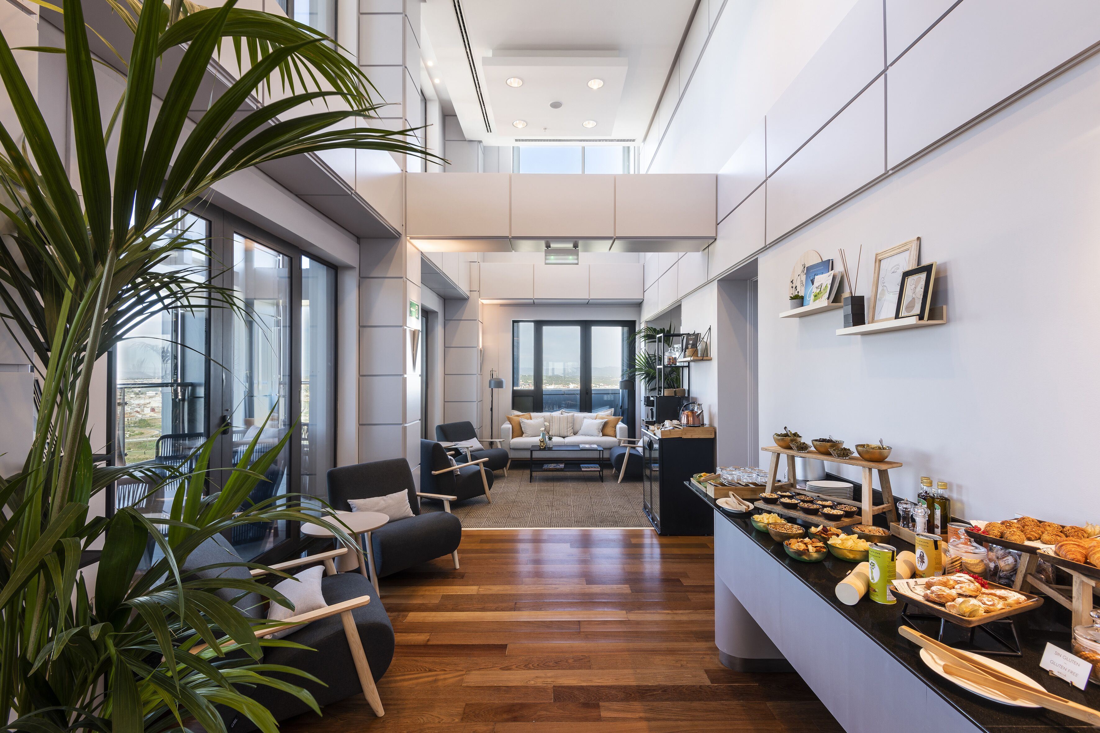Una cocina moderna con barra desayunadora, piso de madera y grandes ventanales con vistas al exterior.