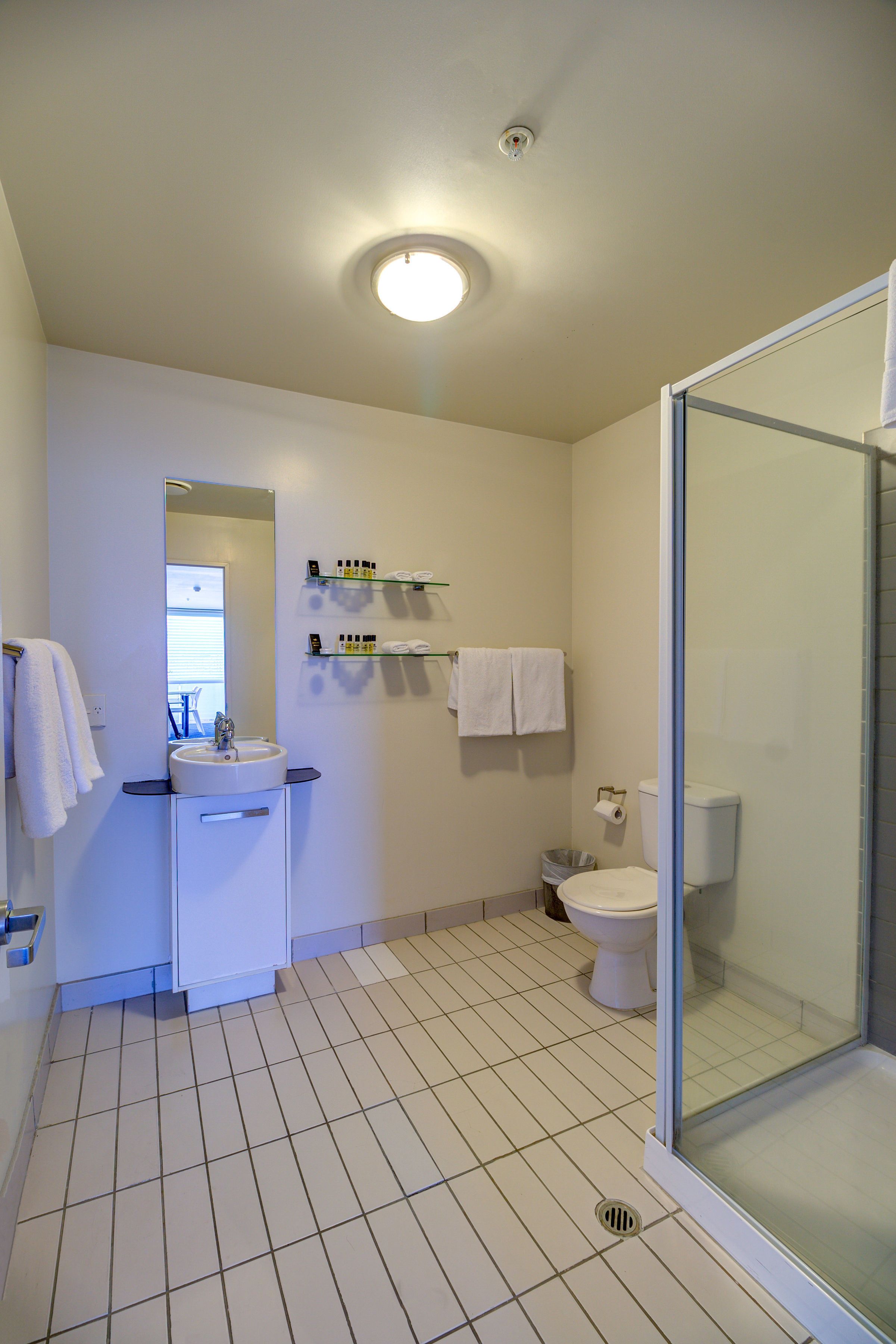 A bathroom with a sink, mirror, toilet, and glass shower enclosure.