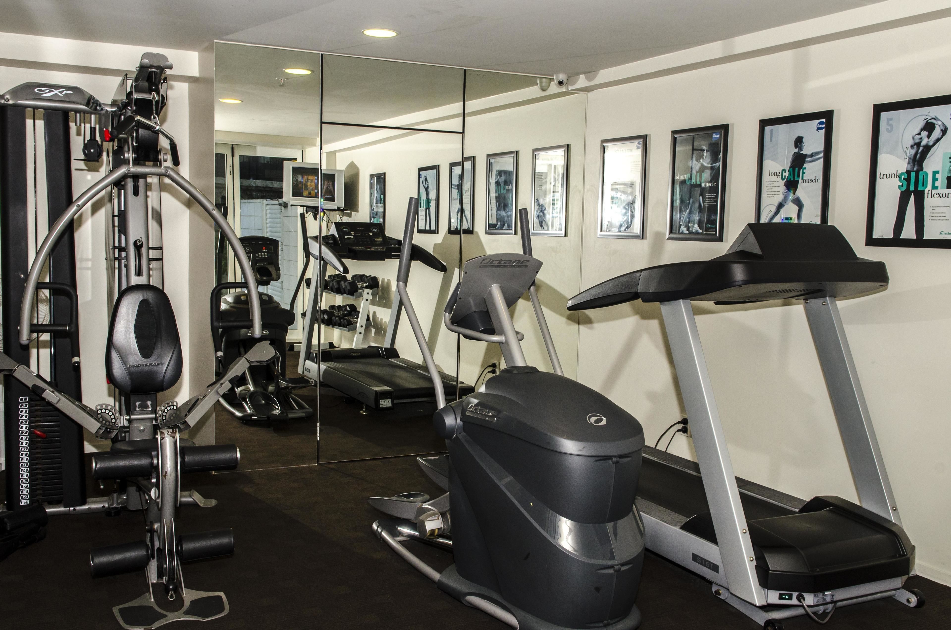 Uma academia com máquinas de cardio, equipamentos de musculação e espelhos nas paredes.