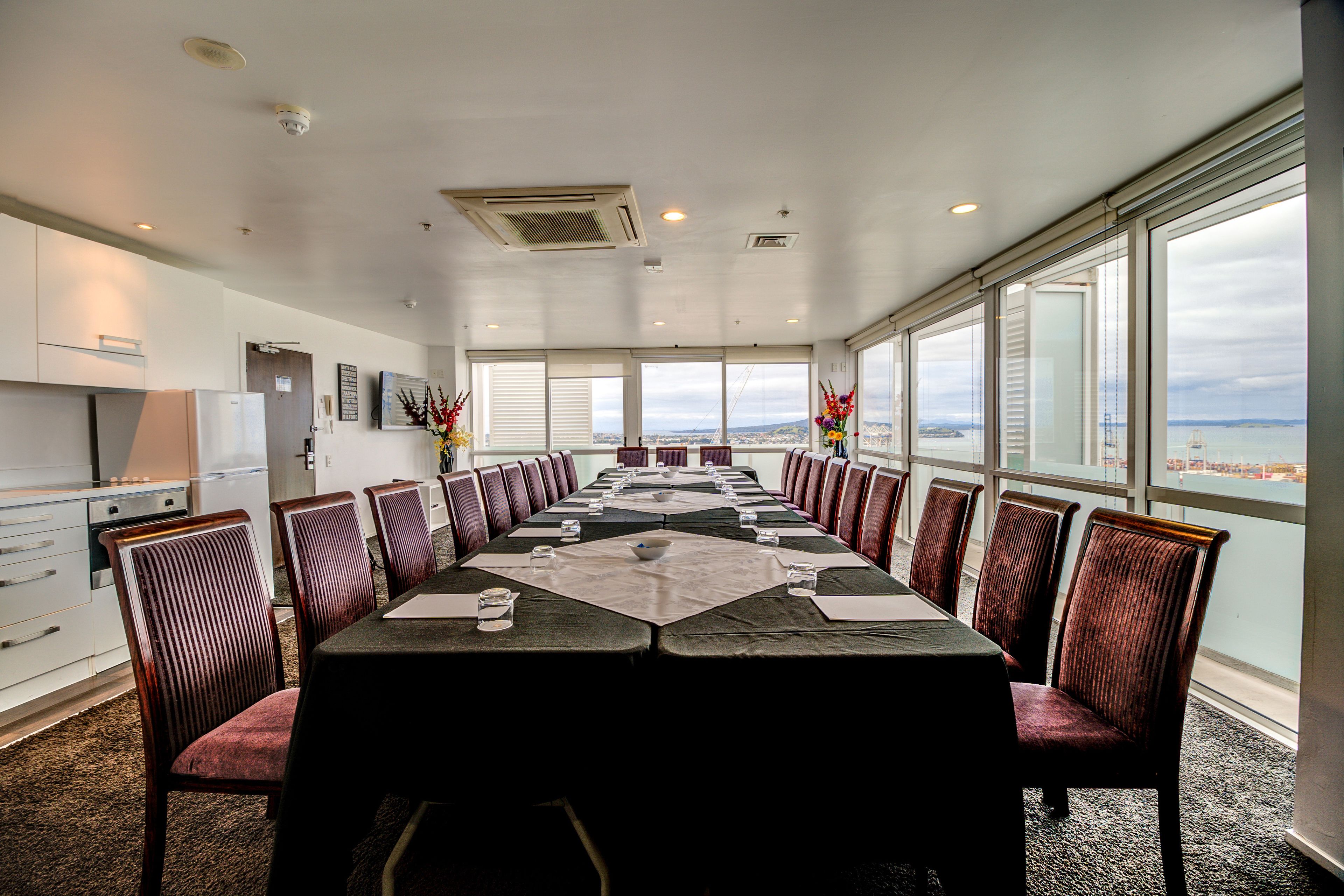 A conference room with a long table, chairs, and a view of the ocean.