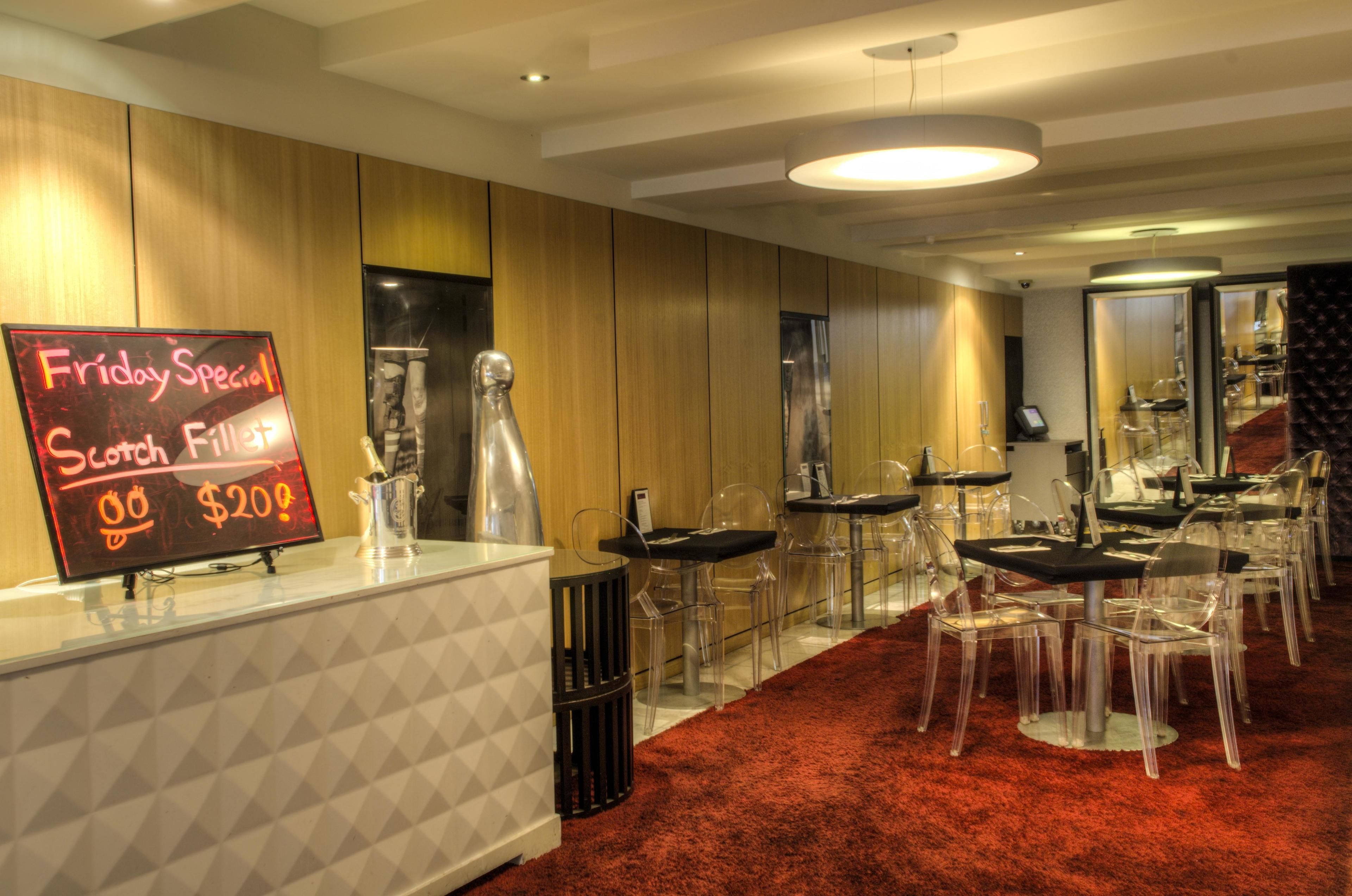 A restaurant with a red carpet, clear chairs, and a sign advertising a Friday special.