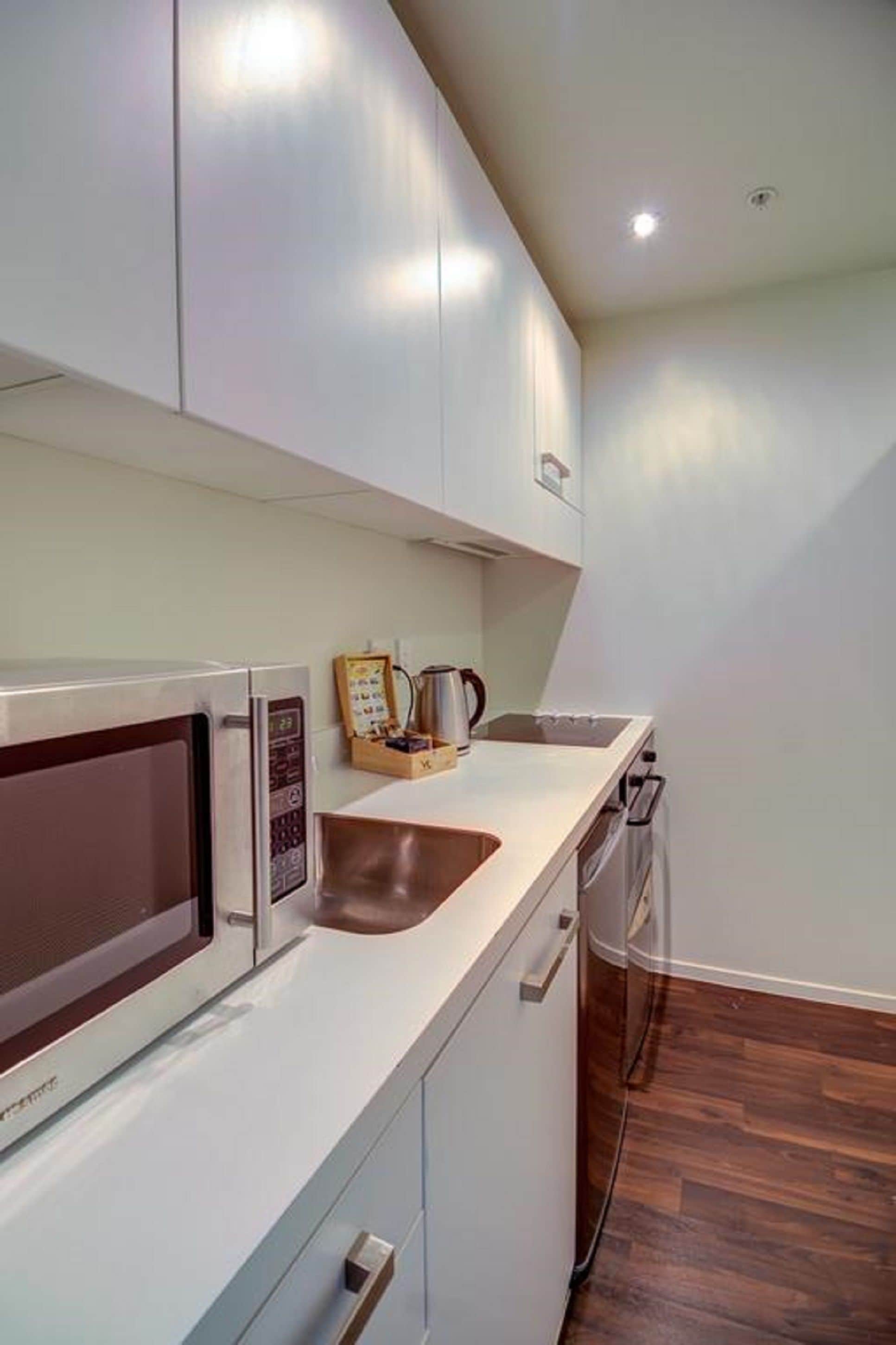 A modern kitchen with white cabinets, a microwave, and a coffee maker on the counter.